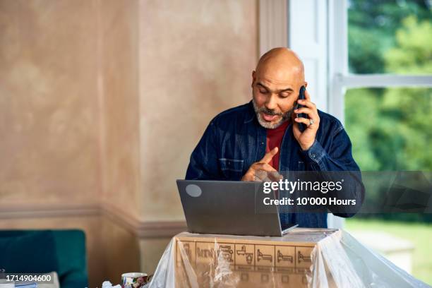 man using laptop in new home - greater london stock pictures, royalty-free photos & images