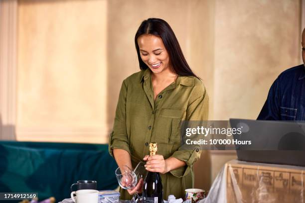 smiling woman with champagne and glasses in new house - good move concept stock pictures, royalty-free photos & images