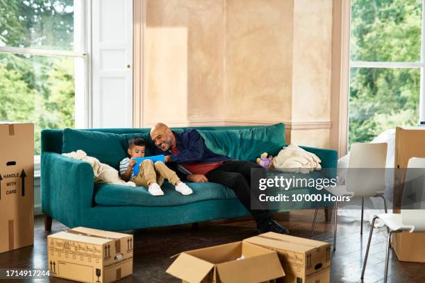 father and son relaxing on sofa in new home - watch stock pictures, royalty-free photos & images