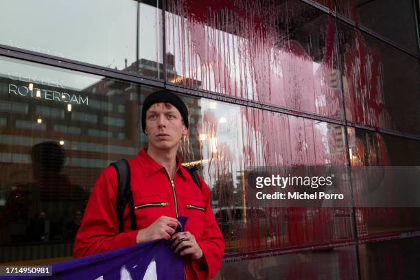 Climate activist stands by a window of the Rotterdam Harbour office covered in red paint in protest against the 'crucial role the harbour plays in...