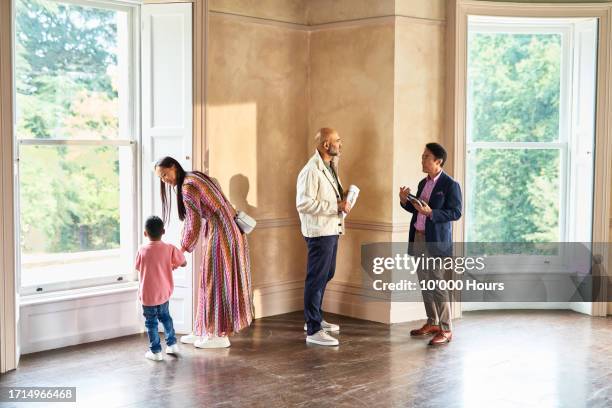 real estate agent taking to mature man as mother and son look out of window - greater london stock pictures, royalty-free photos & images