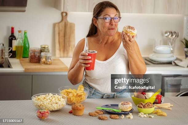 greedy woman enjoying eating a doughnut and drinking cola. unhealthy eating concept - fat people eating donuts stock pictures, royalty-free photos & images