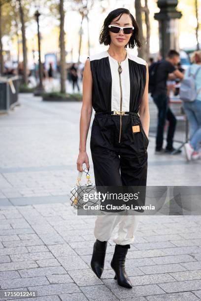 Chriselle Lim wears a black and white jumpsuit, black boots, Louis Vuitton white checked bag and white sunglasses, outside Louis Vuitton, during the...