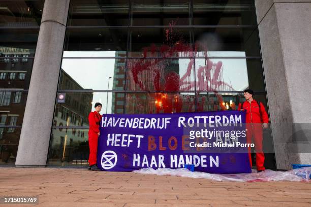 Protestors holding a banner that reads 'Harbour Rotterdam has blood on her hands' have thrown red paint over the windows of the Rotterdam Harbour...