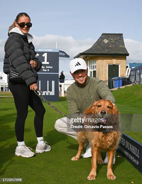 Richard Mansell of England and his Wife, Ellie, pose for a photo alongside their dog, Arnie during a practice round prior to the Alfred Dunhill Links...