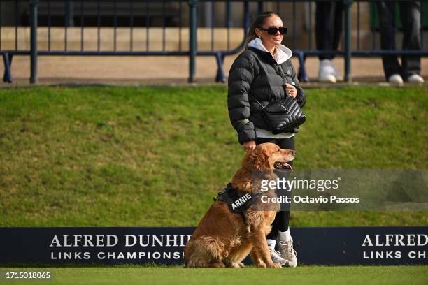 Ellie Mansell, Wife of Richard Mansell of England looks on with their dog, Arnie during a practice round prior to the Alfred Dunhill Links...