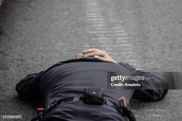 An Israeli police officer lying flat on the ground shields his head with hands during a rocket attack launched from Gaza as rockets are intercepted...