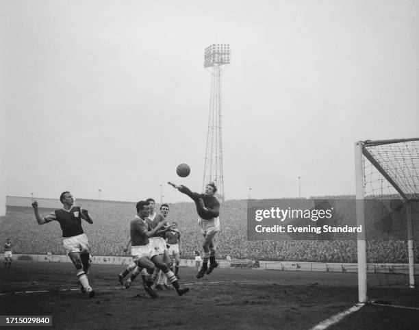 Chelsea goalkeeper Reg Matthews jumps to make a save as players including Chelsea's Mel Scott and West Ham's Vic Keeble look on during a match at...