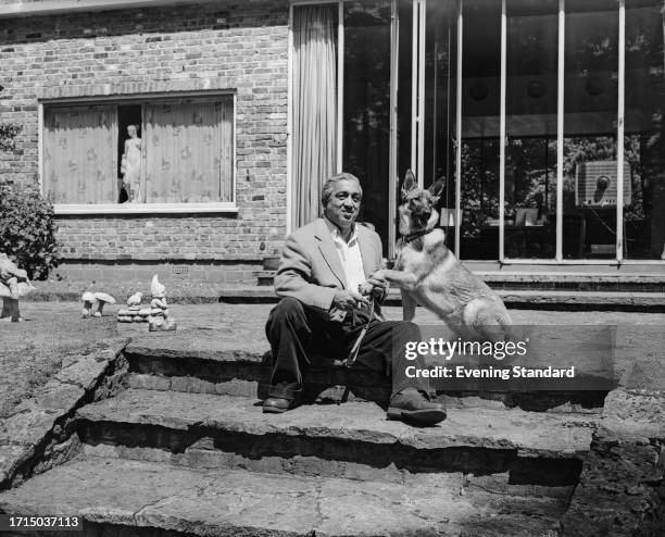 Pratap Singh Rao Gaekwad , the Maharajah of Baroda, sitting on garden steps with an Alsatian dog, June 22nd 1959.