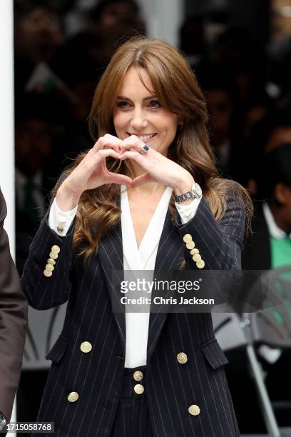 Catherine, Princess of Wales makes a heart sign with her hands during her visit to Fitzalan High School as she celebrates the beginning of Black...