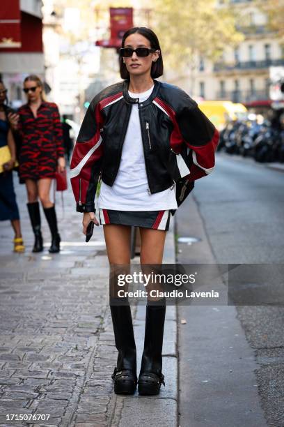 Alexandra Guerain wears a black and red leather moto jacket, matching mini skirt, white t-shirt, black boots and black bag, outside AZ Factory,...