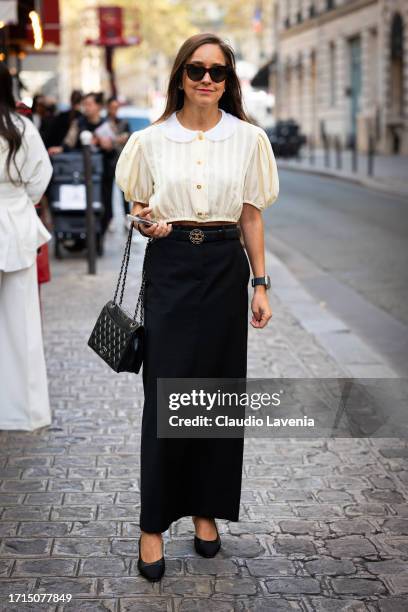 Guest wears a cream shirt, black maxi skirt, Chanel belt, bag and shoes, outside AZ Factory, during the Womenswear Spring/Summer 2024 as part of...