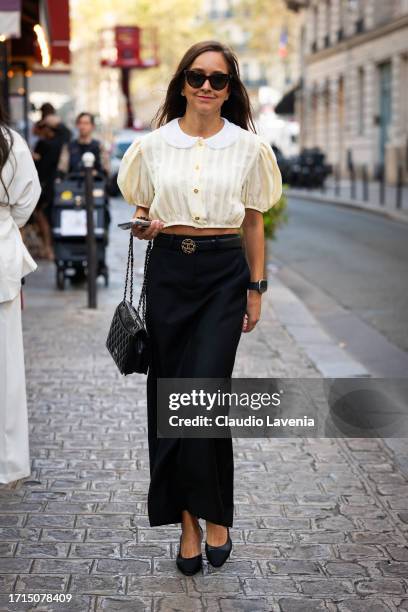 Guest wears a cream shirt, black maxi skirt, Chanel belt, bag and shoes, outside AZ Factory, during the Womenswear Spring/Summer 2024 as part of...