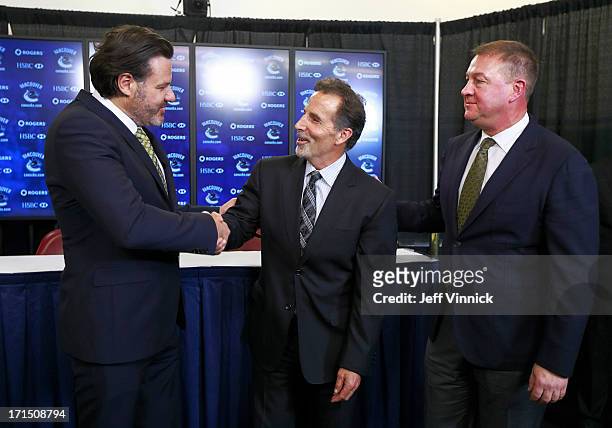 Vancouver Canucks General Manager Mike Gillis looks on as Canucks owner Francesco Aquilini shakes hands with new head coach John Tortorella during a...