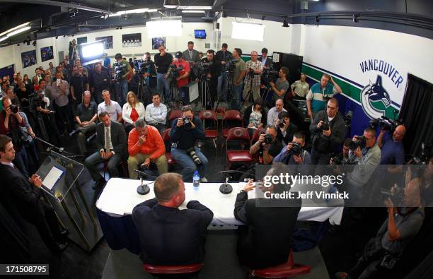 Vancouver Canucks General Manager Mike Gillis looks on as new Canucks head coach John Tortorella talks to the media during a press conference at...