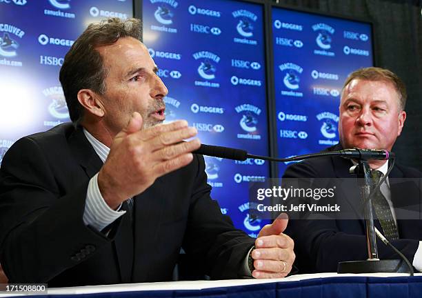 Vancouver Canucks General Manager Mike Gillis looks on as new Canucks head coach John Tortorella talks during a press conference at Rogers Arena June...