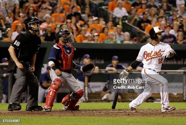 Home plate umpire Mike DiMuro and catcher Carlos Santana of the Cleveland Indians look on as Alexi Casilla of the Baltimore Orioles follows his three...