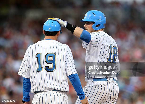 Cody Regis of the UCLA Bruins pats first base coach Jake Silverman on the head after hitting an RBI single in the fourth inning against the...