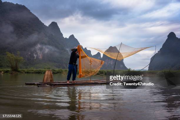 a fisherman on raft fishing in the river in north vietnam - cao bang stock pictures, royalty-free photos & images