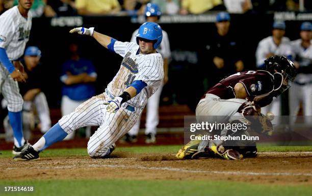 Cody Regis of the UCLA Bruins slides into home to score a run ahead of the throw to catcher Nick Ammirati of the Mississippi State Bulldogs in the...