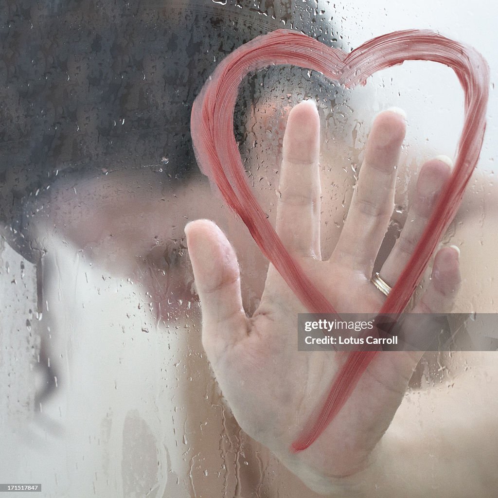 Woman with hand on heart shape on shower door