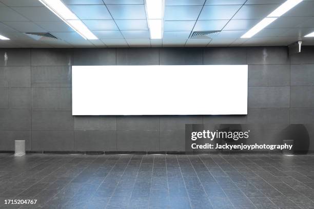 on the wall of a subway station, a blank billboard advertising banner media display - metro mall stock-fotos und bilder