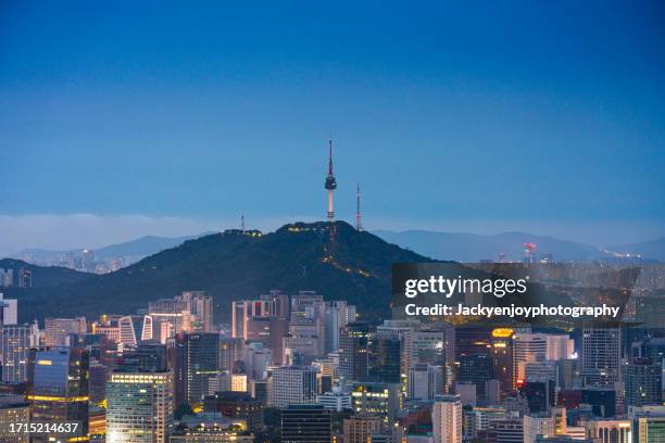 view from inwang mountain at dusk of namsan seoul tower in the centre of seoul's metropolis lighted by lights. south korea's seoul - namsan seoul stock pictures, royalty-free photos & images