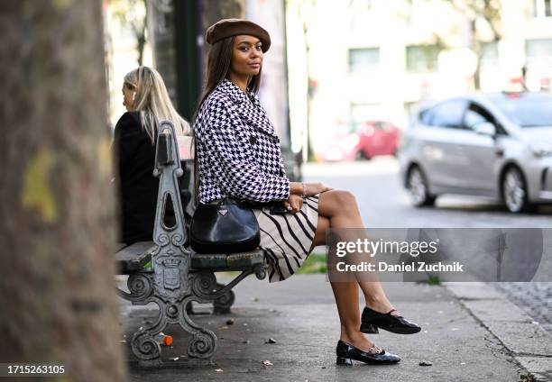 Wendy Thembelihle Juel is seen wearing a black and white chevron jacket, cream and black skirt, black Prada bag, black shoes and a brown beret...