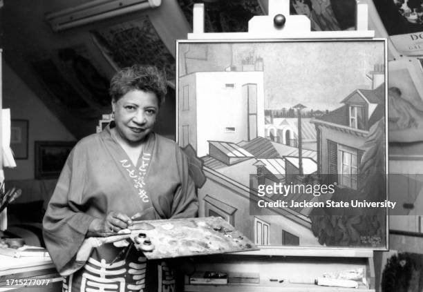 Lois Mailou Jones , artist and Professor of Design in the College of Fine Arts at Howard University poses for a photograph near a painting.