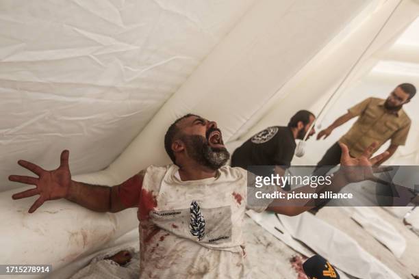 October 2023, Palestinian Territories, Gaza City: A Palestinian man reacts next to the body of his nephew, who was killed in Israeli airstrikes on...