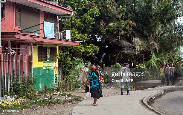 Local residents walk in front a bakery where four Asian expatriates were murdered, in Port Moresby on June 26, 2013. Four Chinese nationals have been...
