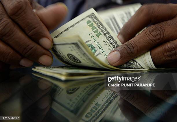 An Indian man counts US dollar notes at a local currency exchange shop in Mumbai on June 26, 2013. India's rupee touched a record low of more than 60...