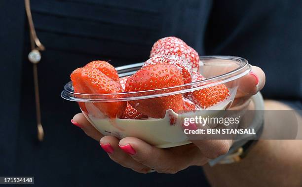 Spectator carries strawberries and cream on day three of the 2013 Wimbledon Championships tennis tournament at the All England Club in Wimbledon,...