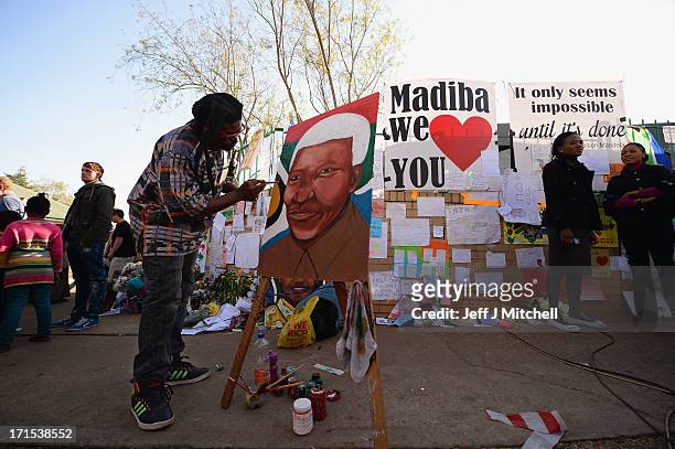 Man paints a picture as people gather to leave messages of support for former South African President Nelson Mandela outside the Mediclinic Heart...