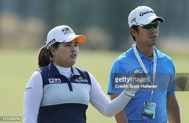 Inbee Park of South Korea walks alongside Gi Hyeob Nam, her coach and fiancé during a practice round prior to the start of the 2013 U.S. Women's Open...