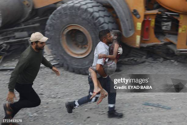 Member of the Palestinian civil defence carries a wounded boy rescued from the rubble of the Tattari family home which was destroyed in an Israeli...