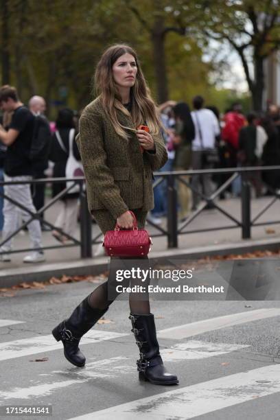 Veronika Heilbrunner wears a green khaki knit cardigan / jacket, a matching mini short skirt, a red leather bag, tights, black knee-high leather...