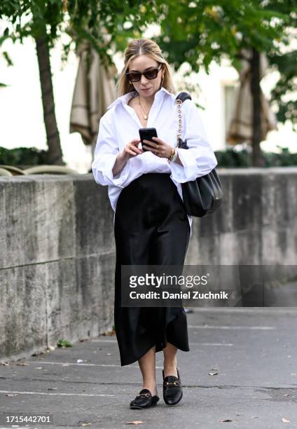 Caroline Grosso is seen wearing a white button shirt, black skirt and black shoes with black and gold bag outside the Zimmermann show during the...
