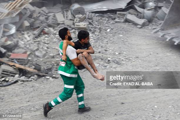 Member of the Palestinian civil defence carries a wounded boy rescued from the rubble of the Tattari family home which was destroyed in an Israeli...