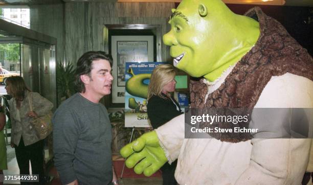 View of American actor Peter Gallagher and a costumed 'Shrek' performer at a screening of 'Shrek,' New York, New York, May 15, 2001.