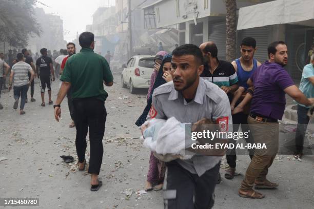 Member of the Palestinian civil defence runs with an infant rescued from the rubble of the Tattari family home which was destroyed in an Israeli...