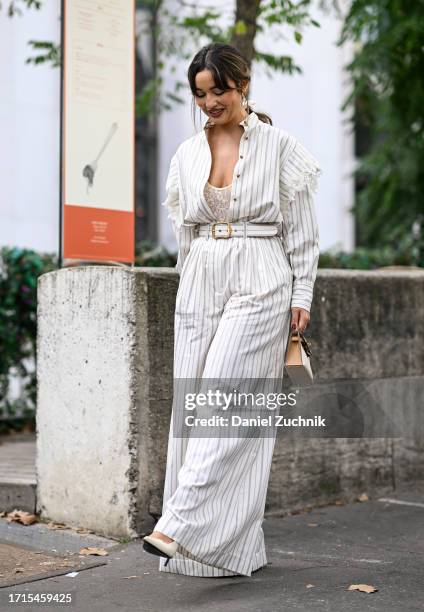 Guest is seen wearing a striped top and pants with white belt and cream and tan mini bag outside the Zimmermann show during the Womenswear...