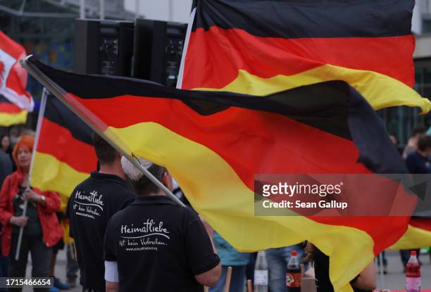 Supporters of the far-right "Zukunft Heimat" movement, including some with black t-shirts that read: "Love of homeland is not a crime," hold up...