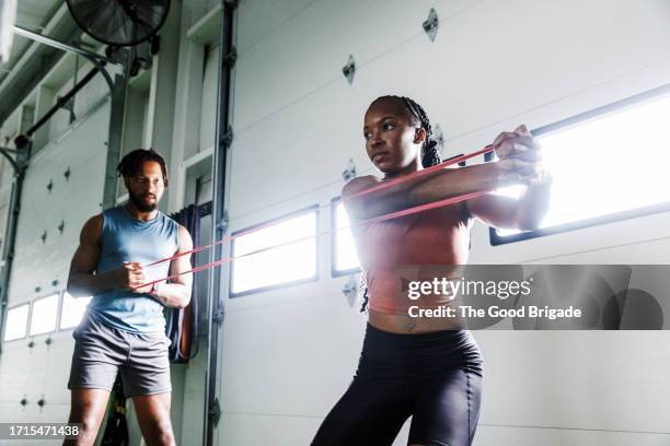 young man and woman exercising with resistance band at gym - waist up stock pictures, royalty-free photos & images