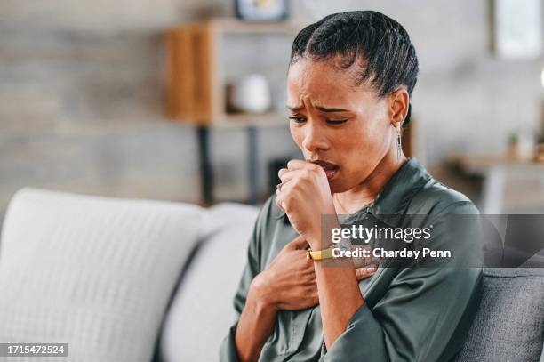 close-up of woman coughing on sofa at home - coughing stock pictures, royalty-free photos & images