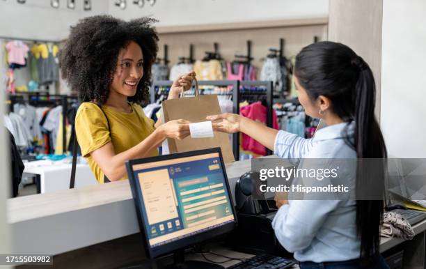 woman shopping at a clothing store and paying to the cashier - kledingwinkel stockfoto's en -beelden