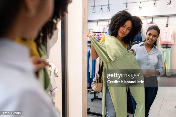 happy woman shopping at the clothing store and trying a dress - jumpsuit stock pictures, royalty-free photos & images