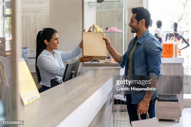 man shopping at a clothing store and paying to the cashier - shop till stockfoto's en -beelden