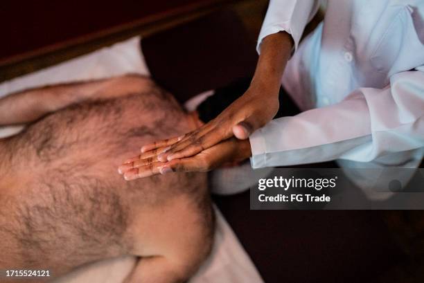thérapeute se frottant les mains avant de commencer à masser un homme dans un spa - se frotter les mains photos et images de collection