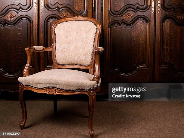 a close-up of an antique cream colored armchair - antiek stockfoto's en -beelden